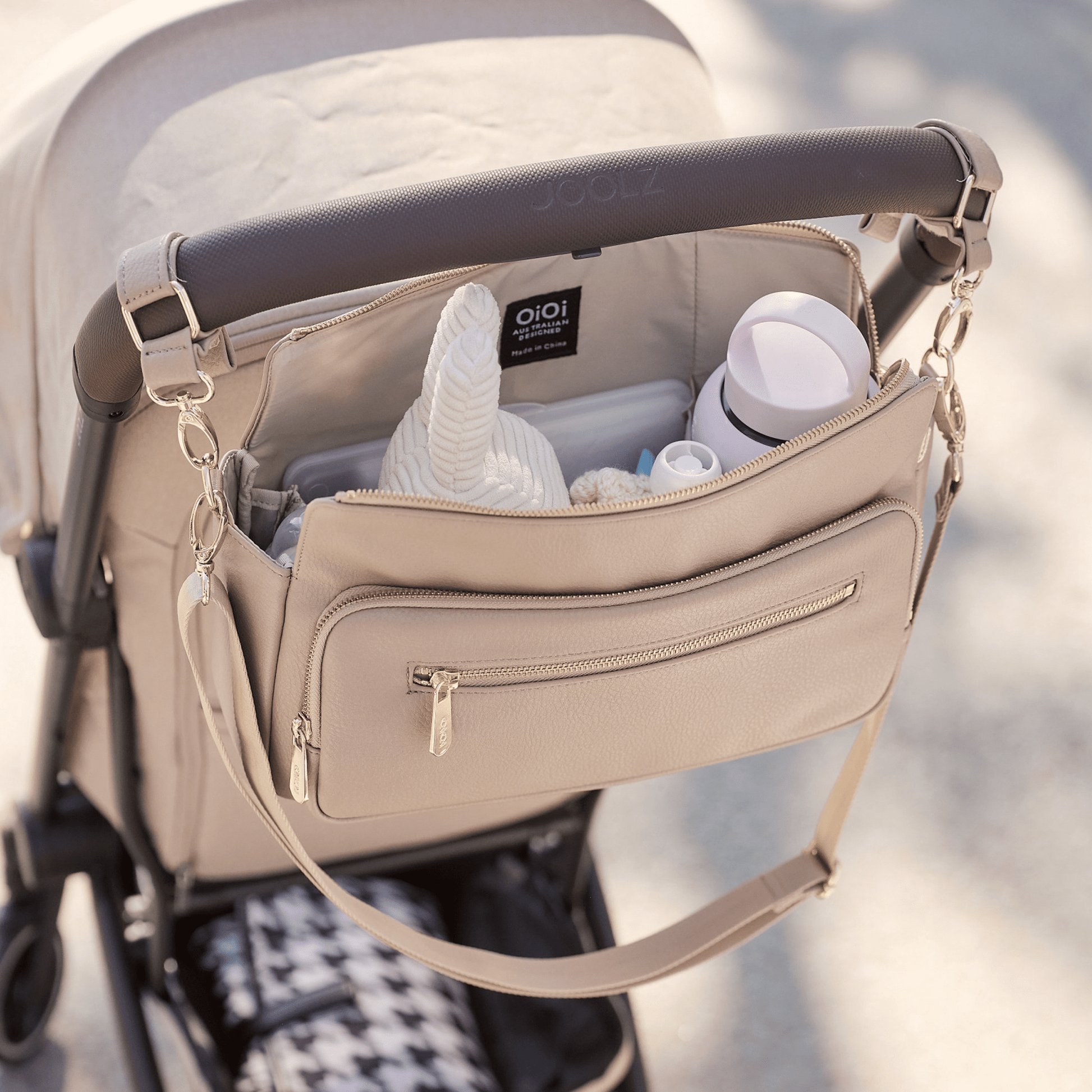 Parent using OiOi oat pram caddy attached to pram - open