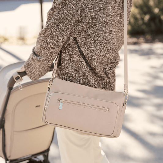 Parent using OiOi oat pram caddy attached to shoulder