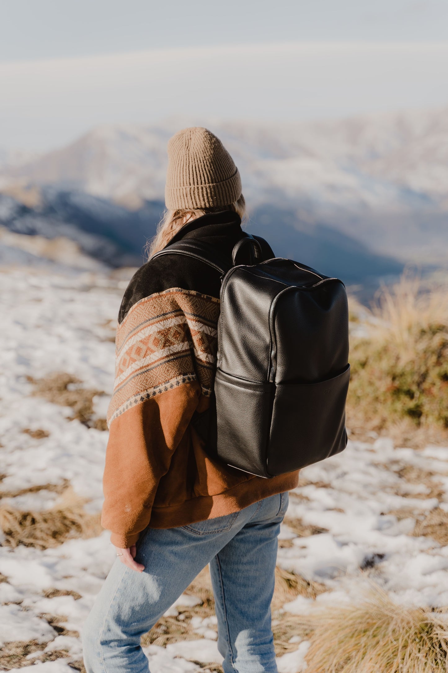 Parent using Oi Oi black dimple faux leather nappy bag backpack on an outdoor family adventure - mum back