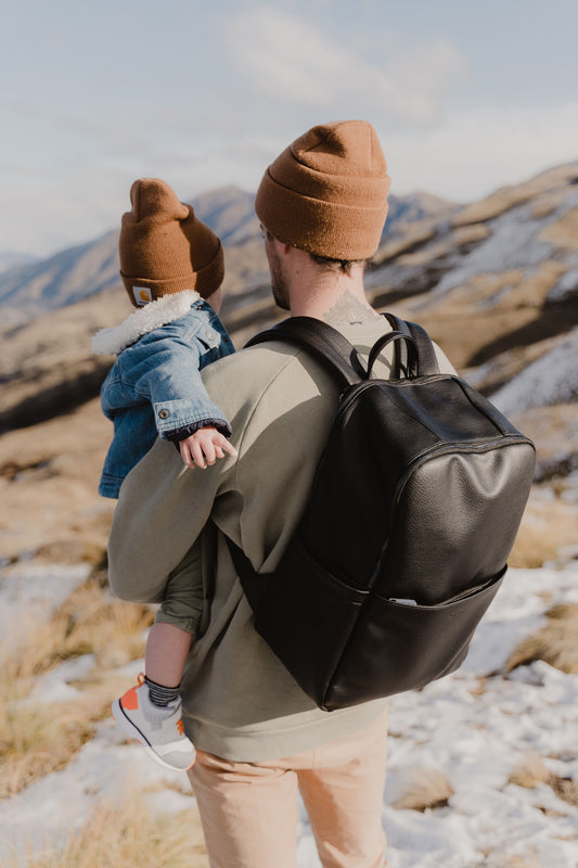 Parent using Oi Oi black dimple faux leather nappy bag backpack on an outdoor family adventure - with dad