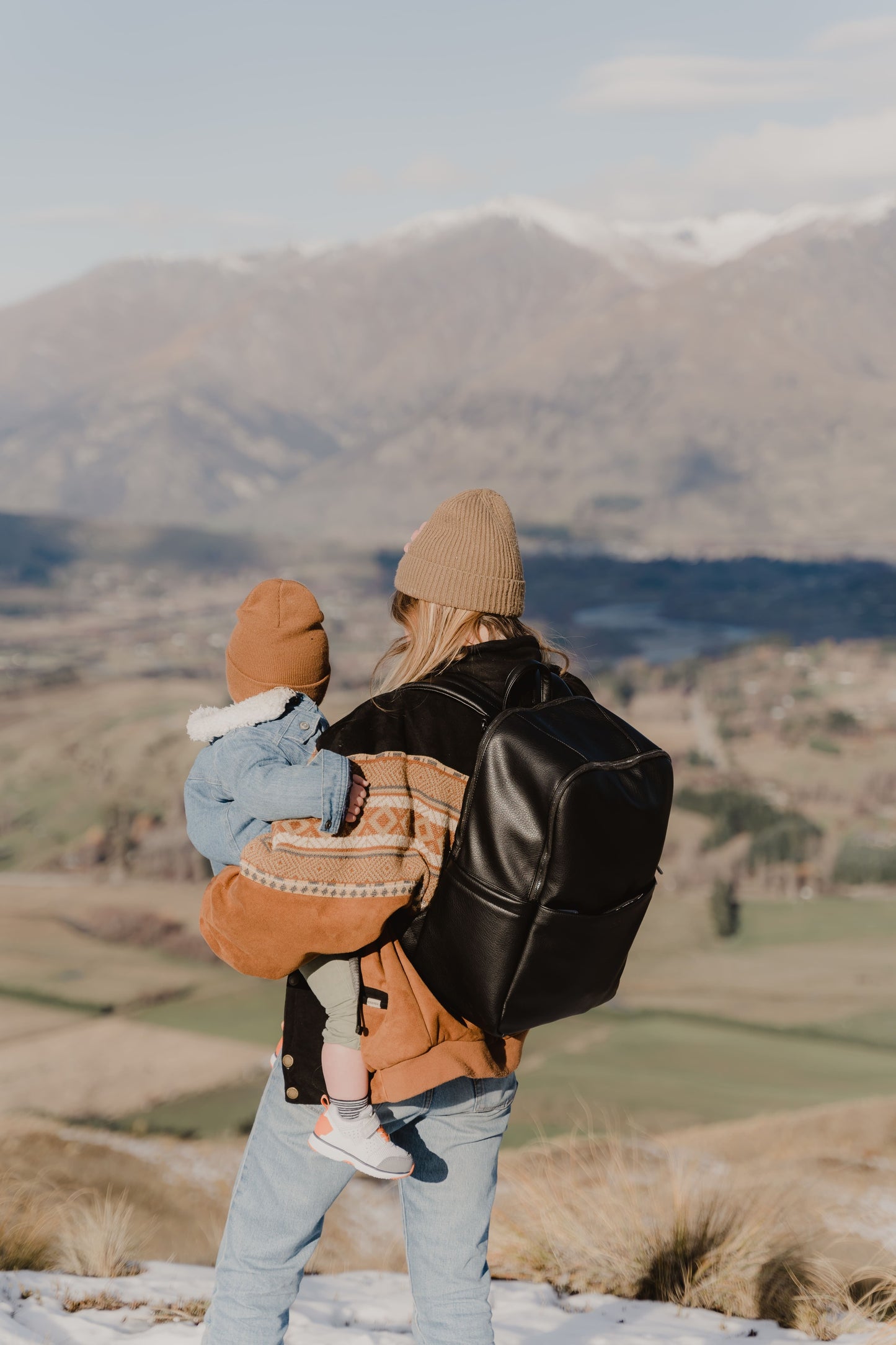Parent using Oi Oi black dimple faux leather nappy bag backpack on an outdoor family adventure - with mum