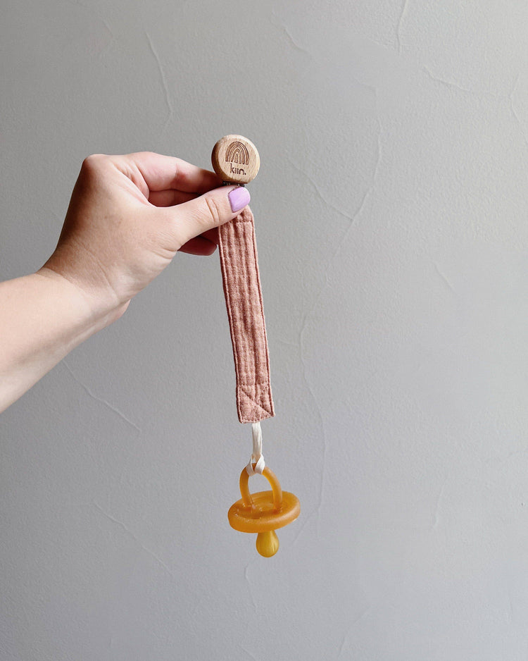 Close-up of organic cotton dummy clip attached to baby's outfit, ready for family picnic