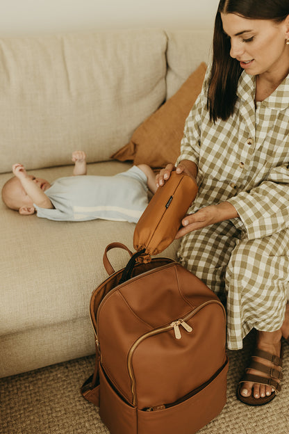 Parent using Oi Oi chestnut brown nappy bag backpack on an outdoor family adventure - couch