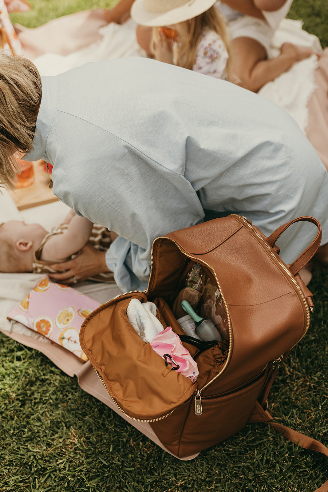 Parent using Oi Oi chestnut brown nappy bag backpack on an outdoor family adventure