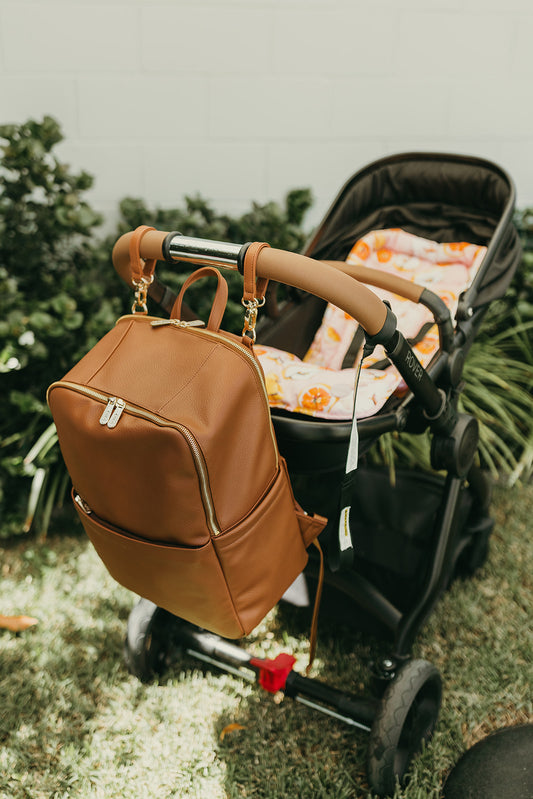 Parent using Oi Oi chestnut brown nappy bag backpack on an outdoor family adventure - pram
